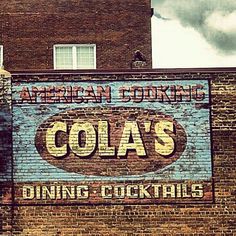 an old sign on the side of a building advertising cola's dining and cocktails