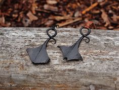 pair of black metal earrings sitting on top of a piece of wood