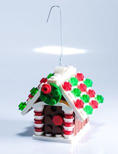 a toy house made out of legos on a white surface with a red and green roof