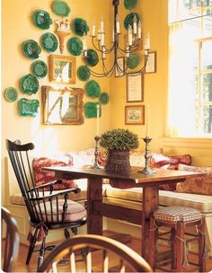 a dining room with yellow walls and green plates on the wall