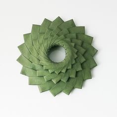 a circular piece of green paper on a white surface with the center cut out to look like a spiral