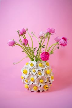 a vase filled with flowers on top of a pink background