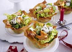 small cups filled with food sitting on top of a white plate next to a red ribbon