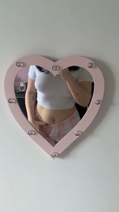 a woman taking a selfie in a heart shaped mirror