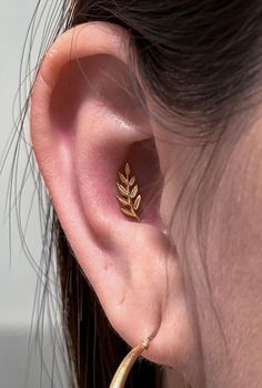 a close up of a person's ear with a leaf design on it