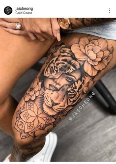 a woman's leg with a tiger and flowers tattoo on it