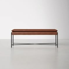 a leather bench sitting on top of a white floor next to a black metal frame