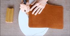 a person is using a knife to cut up a piece of leather on a table