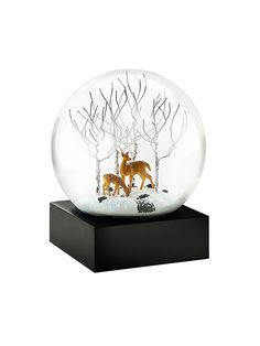 a snow globe with two deer in the woods inside it on a black stand and white background