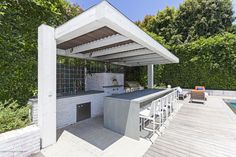 an outdoor kitchen and grill area next to a swimming pool