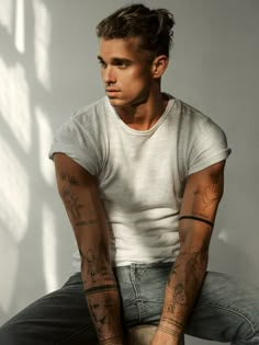 a man with tattoos sitting on a stool