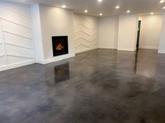 an empty room with a fire place in the center and white walls on both sides