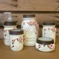 mason jars with flowers painted on them are sitting on a table next to a wooden wall