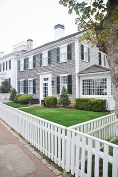 a white picket fence in front of a large house