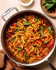 a pan filled with noodles and vegetables on top of a table next to other dishes