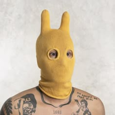 a man with tattoos wearing a yellow bunny mask