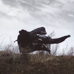 a person laying on top of a hill with their legs in the air while wearing black clothing