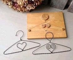 two metal clothes hangers on a wooden board