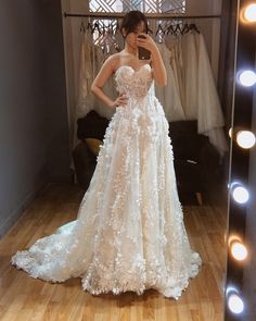 a woman taking a selfie in front of a mirror wearing a wedding dress with flowers on it