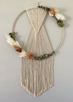 a white wall hanging with flowers and feathers