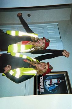 two women standing next to each other in front of a door with their hands up