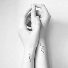 two hands holding each other with tattoos on their arms and wrist, both showing the same letter