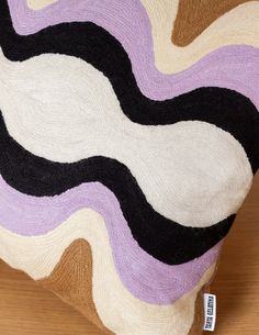 a pillow with an abstract design on the front and back of it, sitting on a wooden floor