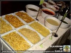 a table topped with lots of trays of food next to bowls of dipping sauce