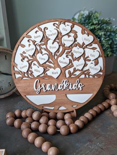 a wooden family tree with names on it next to some beads and a clock that reads grandkids