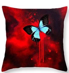 a blue and black butterfly sitting on top of a red cloud filled sky with dark clouds