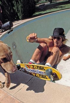 a man riding a skateboard next to a dog on top of a swimming pool