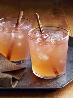 two glasses filled with drinks sitting on top of a metal tray