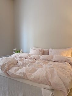 an unmade bed with white sheets and pillows