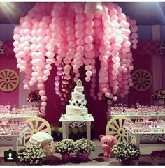 pink balloons are hanging from the ceiling above a table set for a baby's first birthday party