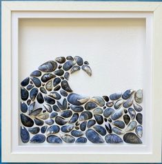 a white frame holding a blue and white paper cut out of shells with a wave in the middle