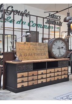 there is a clock on top of an old dresser in the store's shop