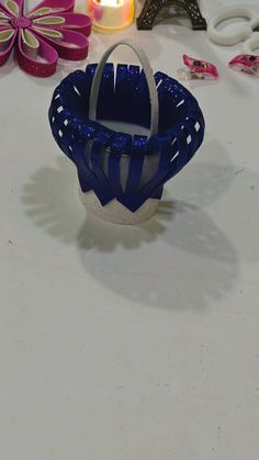 a small blue basket sitting on top of a table next to some scissors and candles