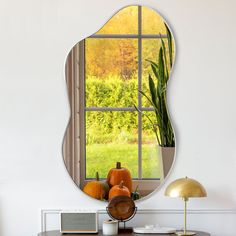 a mirror that is sitting on top of a table next to a vase with pumpkins in it