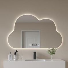 a white bathroom with a cloud shaped mirror above the sink and lights on the wall