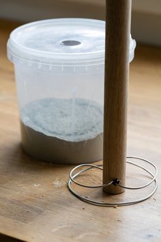 a plastic container sitting on top of a wooden table next to a metal wire holder