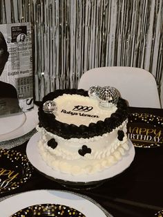 a black and white birthday cake sitting on top of a table next to two plates