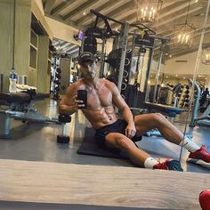 a shirtless man sitting on the ground in a gym