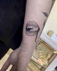 a woman's arm with a black and white lip tattoo on the left forearm