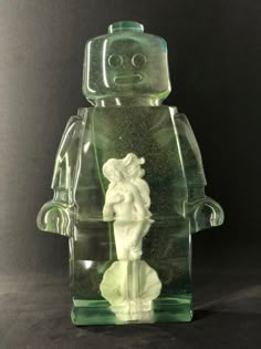 a green glass figurine with a white figure on it's head and arms