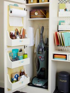 an open closet with various items in it and a vacuum on the shelf next to it