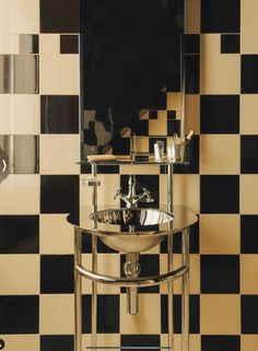 a black and white checkered wall with a sink in the middle, mirror above it