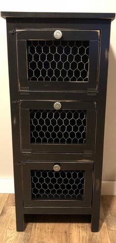 a small black cabinet with two drawers on the bottom and one drawer open to show chicken wire