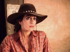 a woman wearing a cowboy hat and looking at the camera with an intense look on her face