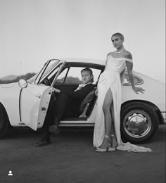 a man and woman standing next to a car