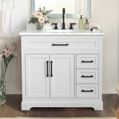 a white bathroom vanity with drawers and a mirror